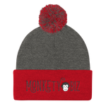 grey beanie with dark red cuff and pompom with Monkety Biz logo in black curvy font on the front cuff, including Monkety Monk cartoon monkey face between Monkety and Biz